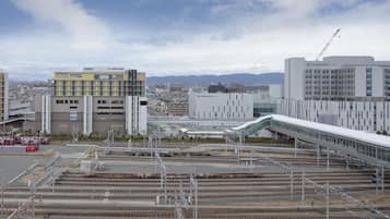A modern hotel with a prominent 'Canedo Hotels' sign, surrounded by urban infrastructure and railway tracks.