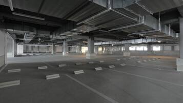 An empty parking garage with concrete pillars and rows of parking spaces.