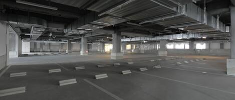Een lege parkeergarage met betonnen pilaren en rijen parkeerplaatsen.