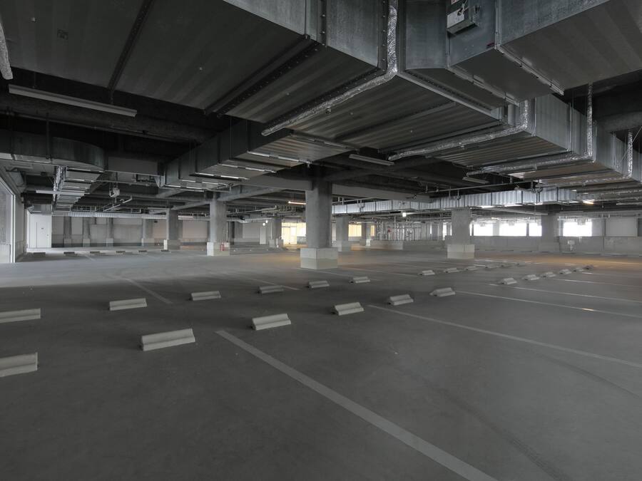 An empty parking garage with concrete pillars and rows of parking spaces.