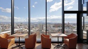 A modern interior with large windows offering a city view. - Candeo Hotels Osaka Kishibe (Suita)