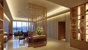 A modern hotel lobby with a reception desk, seating area, and a large window offering a city view. - Candeo Hotels Osaka Kishibe (Suita)