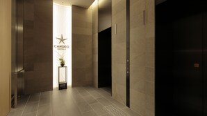 A modern elevator area with a sign for Candeo Hotels, a potted plant, and a tiled floor. - Candeo Hotels Osaka Kishibe (Suita)