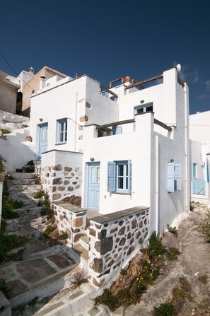 A white building with blue shutters and stone steps.