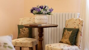 Ein gemütliches Zimmer mit einem Holztisch, zwei Stühlen mit floraler Polsterung und einer Blumenvase.