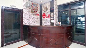 A reception desk with a patterned wallpaper, a clock, and a sign indicating a restaurant.