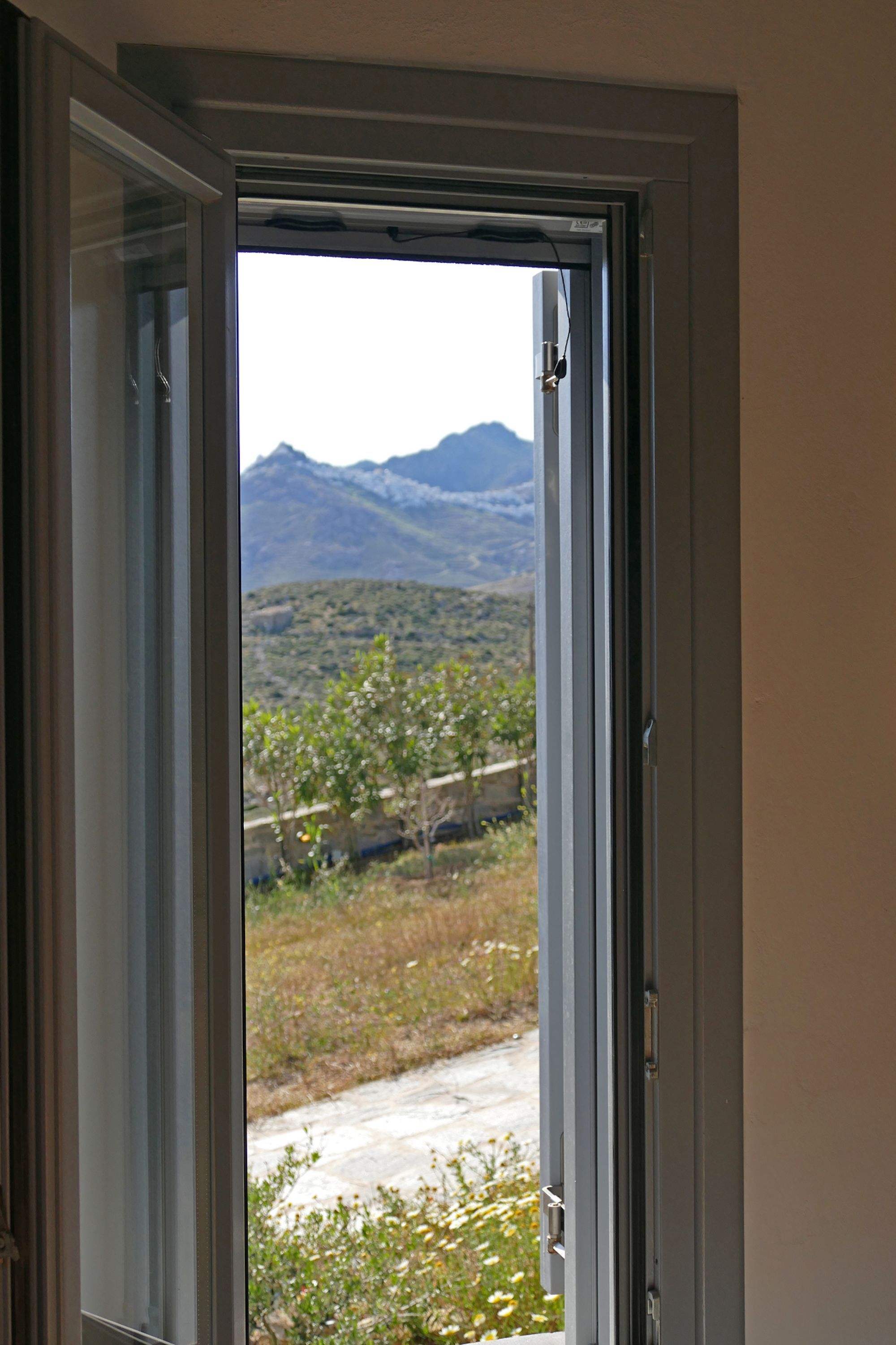 A door opening to a view of mountains and a garden.