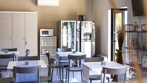 A modern dining area with tables and chairs, a microwave, and a refrigerator. - Riviera Hub (Cisano sul Neva)