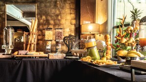 Montaje de bufé con diversos alimentos, una máquina de café y una decoración floral.