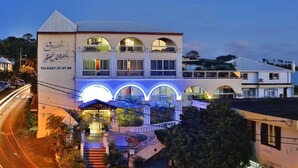 Un hotel con un cartel llamativo, varios ventanales arqueados y una entrada bien iluminada.