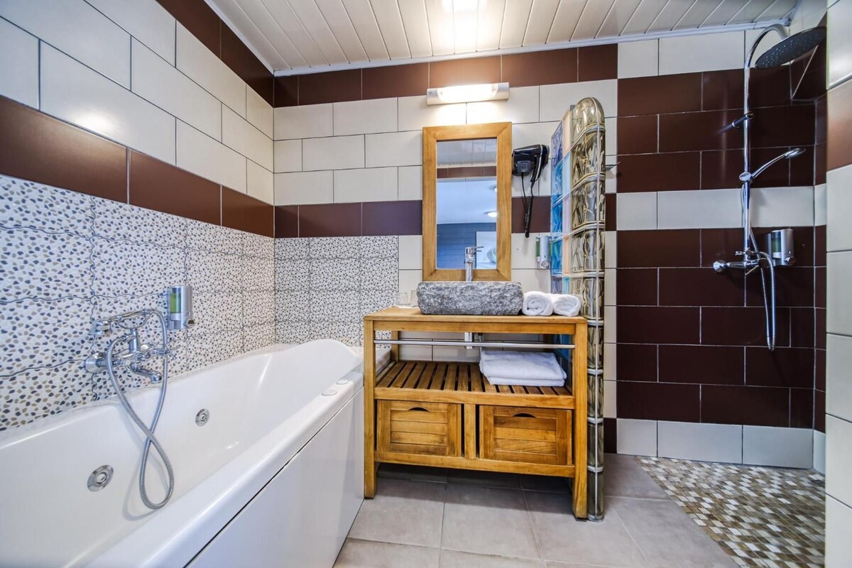 Ein modernes Badezimmer mit einer freistehenden Badewanne, einem hölzernen Waschtisch mit Spiegel und einer Duschkabine.
