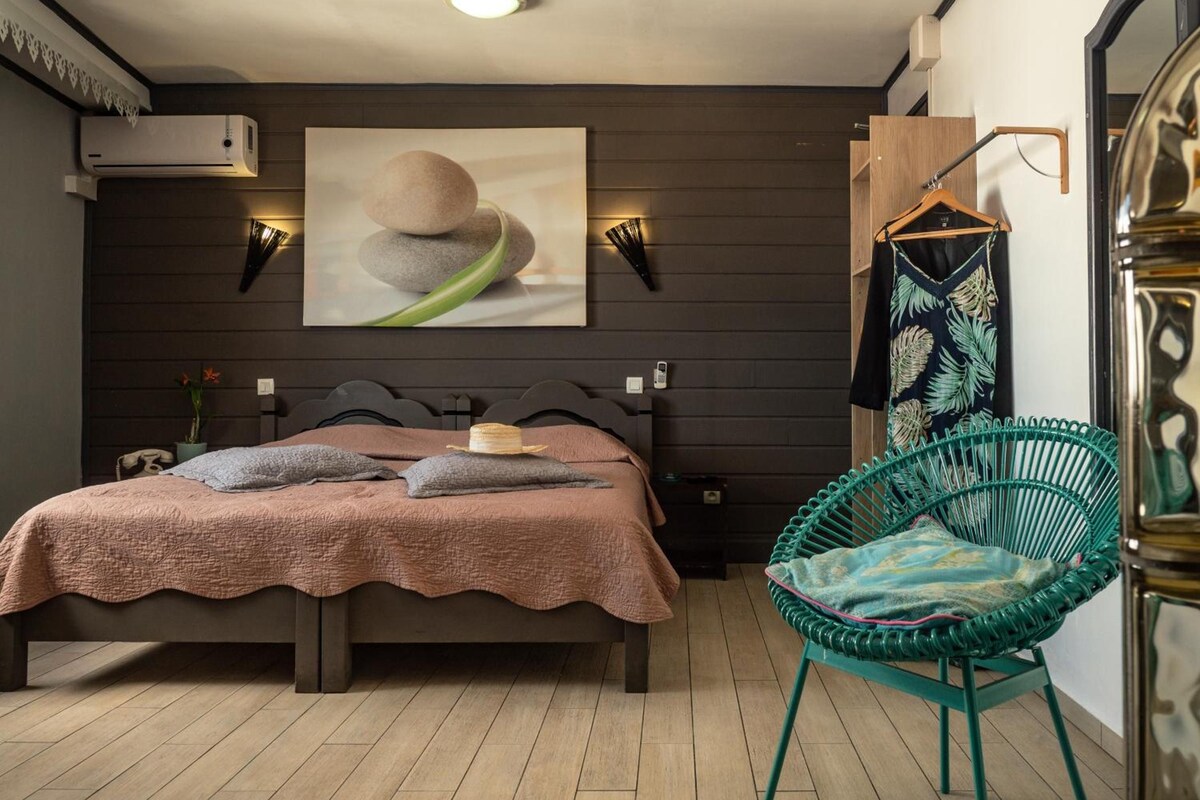 Ein Schlafzimmer mit einem Bett, einem Sessel, einer Wand-Klimaanlage und einem Gemälde.