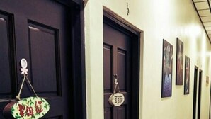 Un pasillo de hotel con puertas de madera oscura, suelo de baldosas y cuadros enmarcados en las paredes.