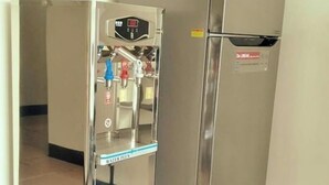 Un refrigerador de acero inoxidable con dispensador de agua en una habitación con piso de baldosas.
