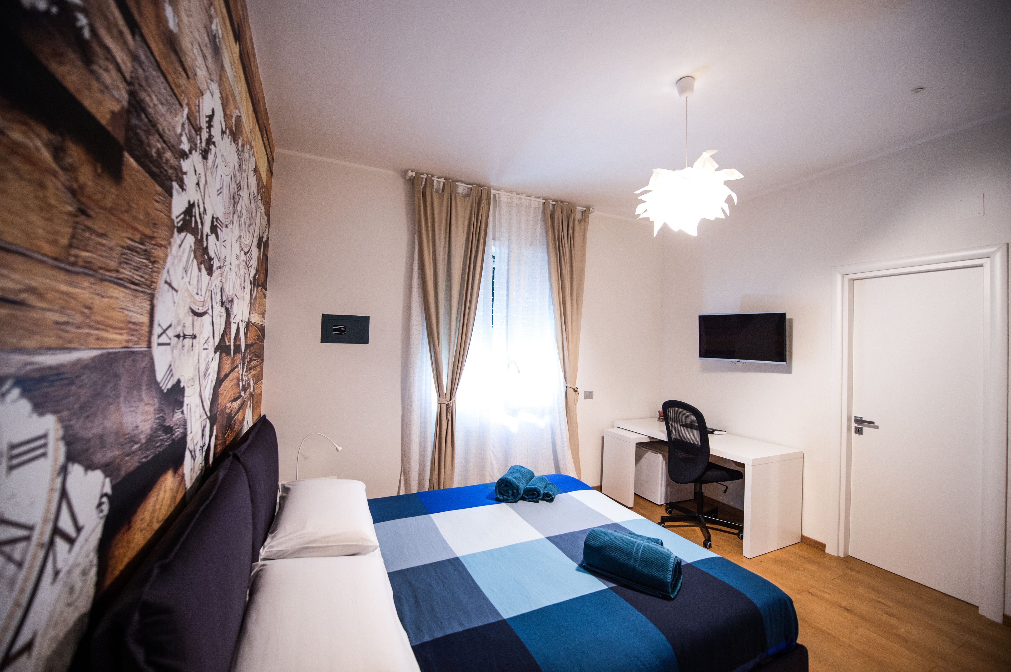 Een hotelkamer met een bed, een bureau, een stoel, een televisie en een deur.