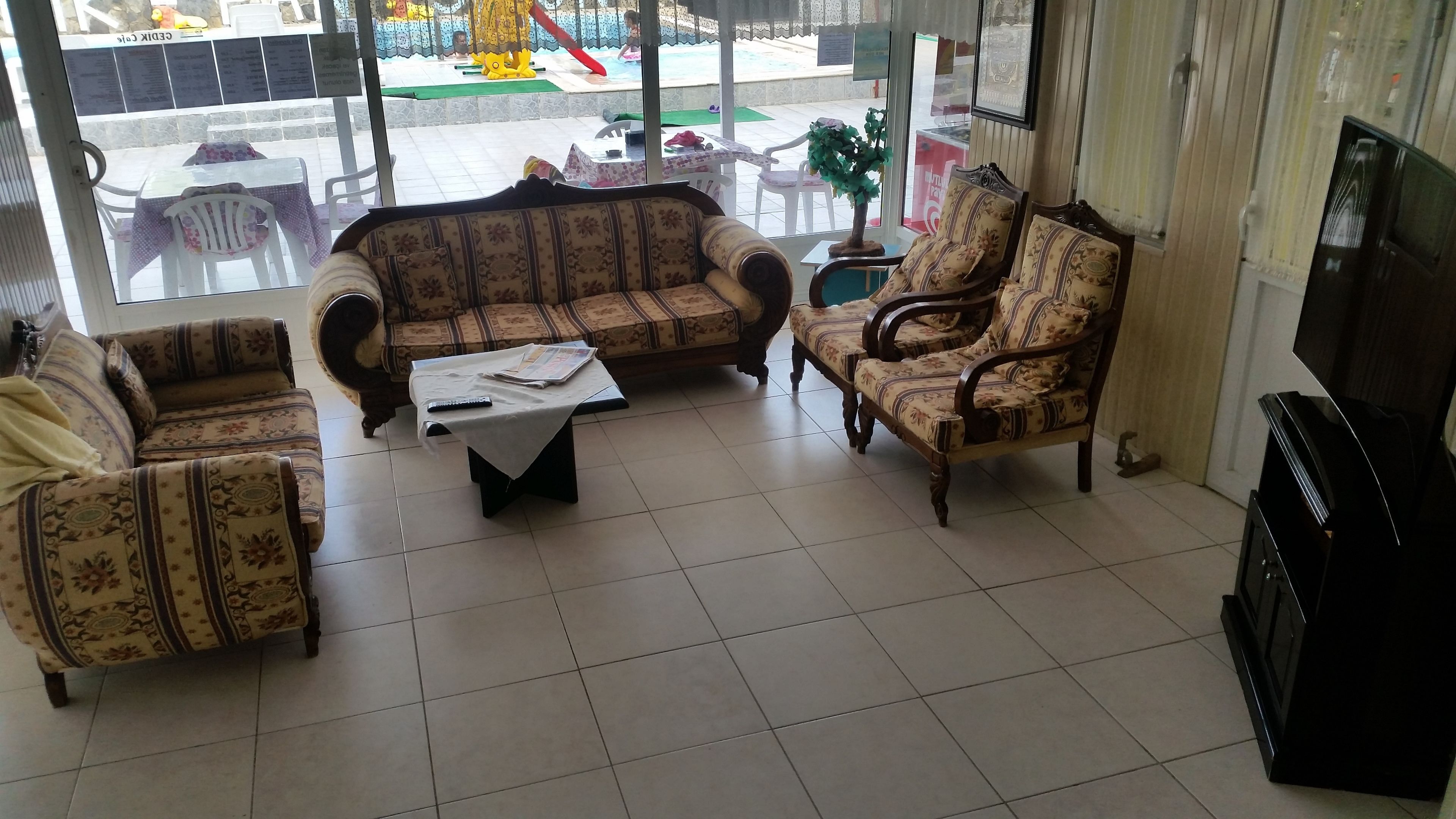Una sala de estar con sofás estampados, una mesa de centro y un televisor.