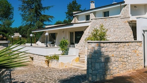 Una casa moderna con fachada de piedra, un porche cubierto y una escalera de piedra que lleva a la entrada.