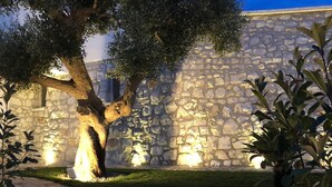 Un edificio de piedra con un camino de piedra que conduce a un área verde con árboles.