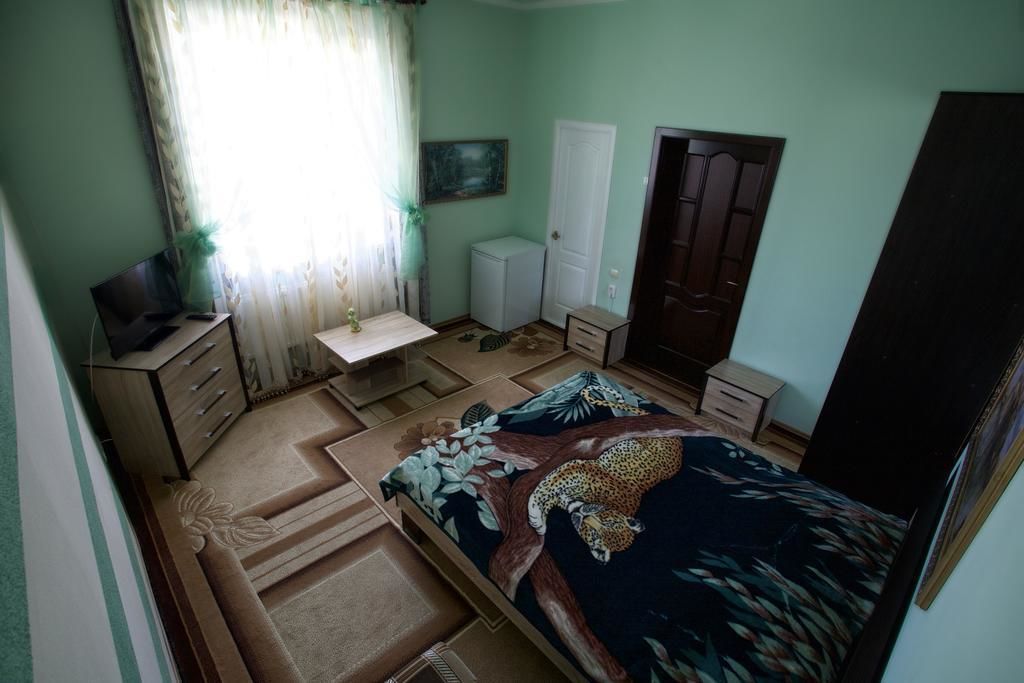 A bedroom with a bed, a desk, a wardrobe, and a television.