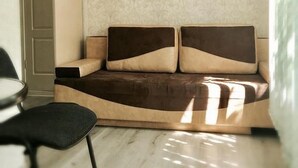 Uma sala de estar moderna com um sofá, uma poltrona e papel de parede estampado.