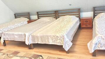 A room with three beds arranged in a row, each with a wooden headboard and a patterned bedspread.