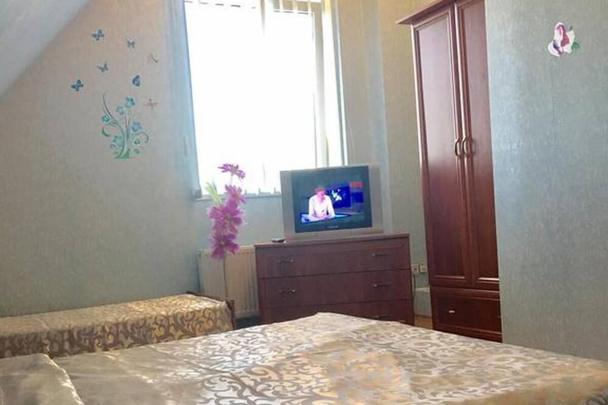 Quarto com cama, televisão, guarda-roupa e janela com cortinas.