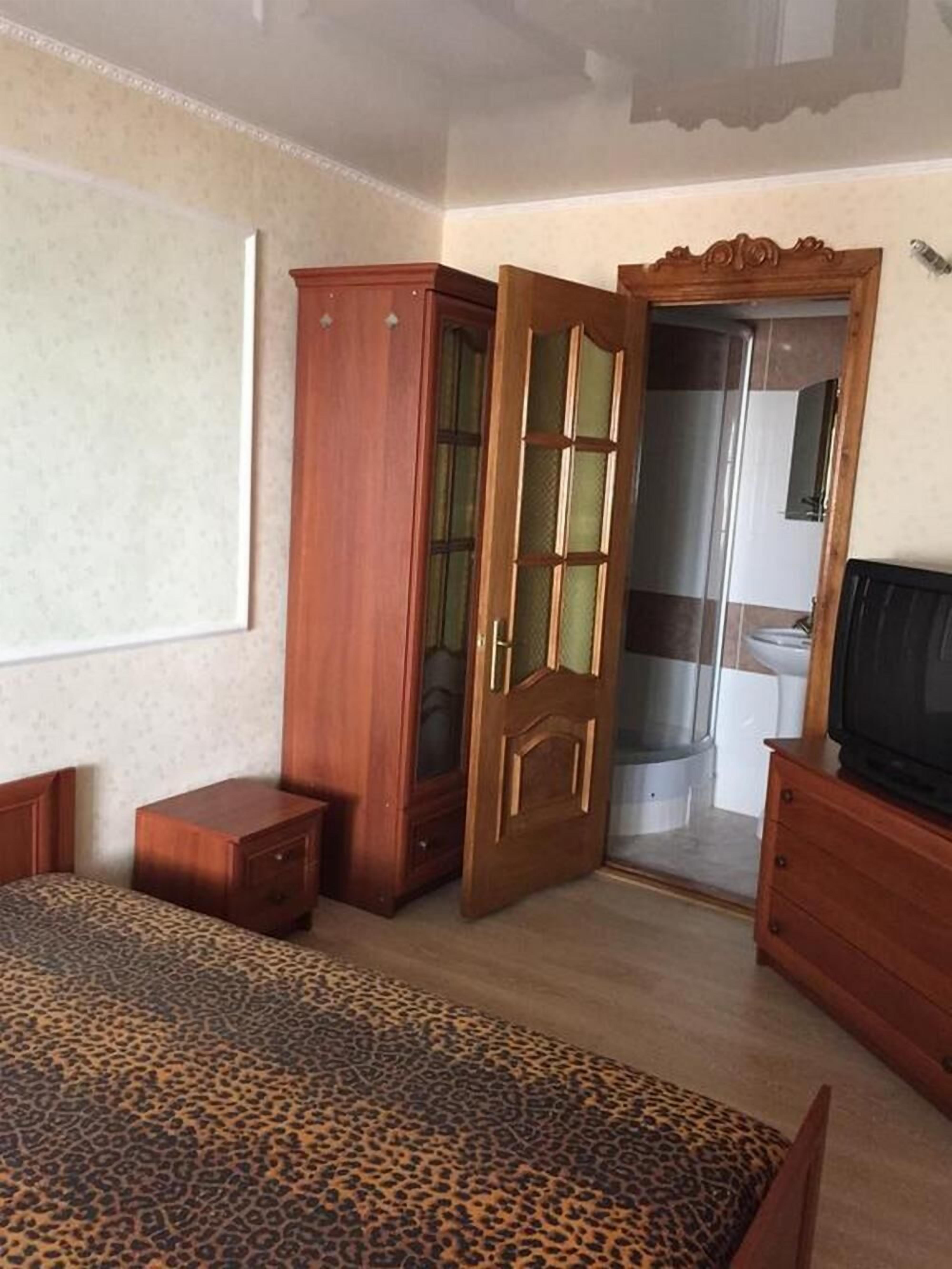 Een slaapkamer met een bed, een kledingkast, een televisie en een badkamer die door een deur zichtbaar is.