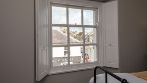 A room with a large window offering a view of a street and buildings. - Hamilton House Holiday Apartments (Downpatrick)