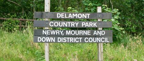 A wooden signpost with text indicating directions to Delamont Country Park and Newry, Mourne, and Down District Council.