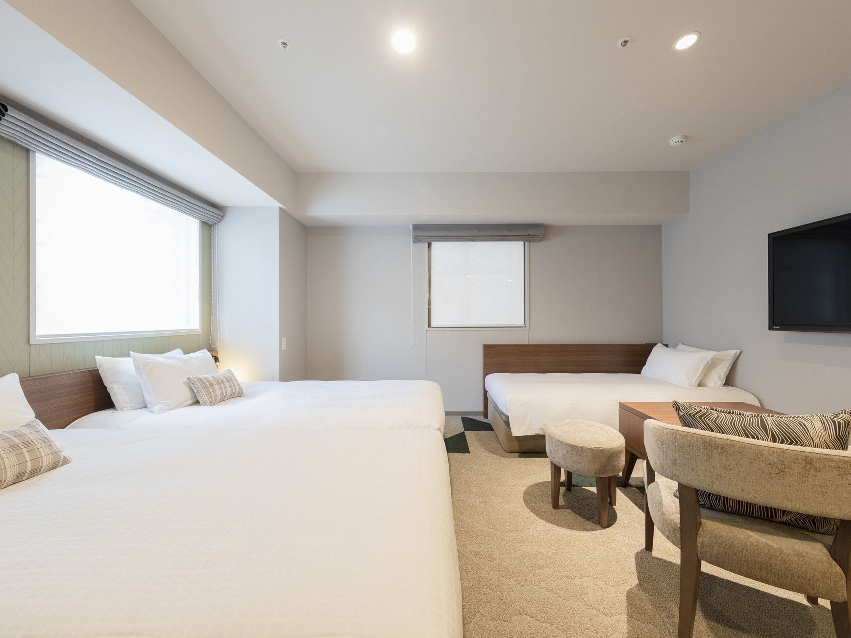 Une chambre d’hôtel avec deux lits, un canapé, une télévision et une fenêtre.