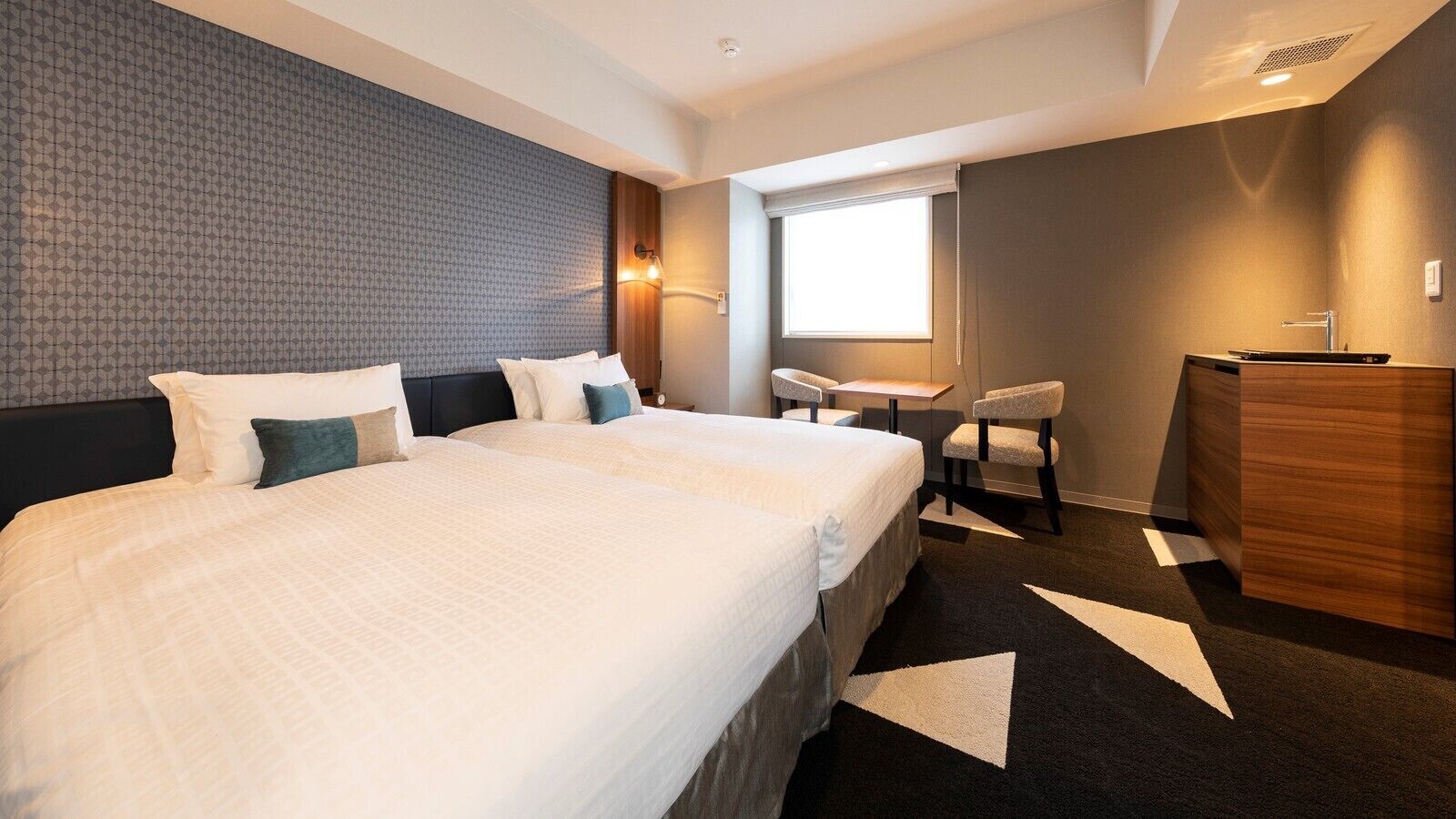 Une chambre d’hôtel avec un grand lit, un bureau, une chaise et une commode.