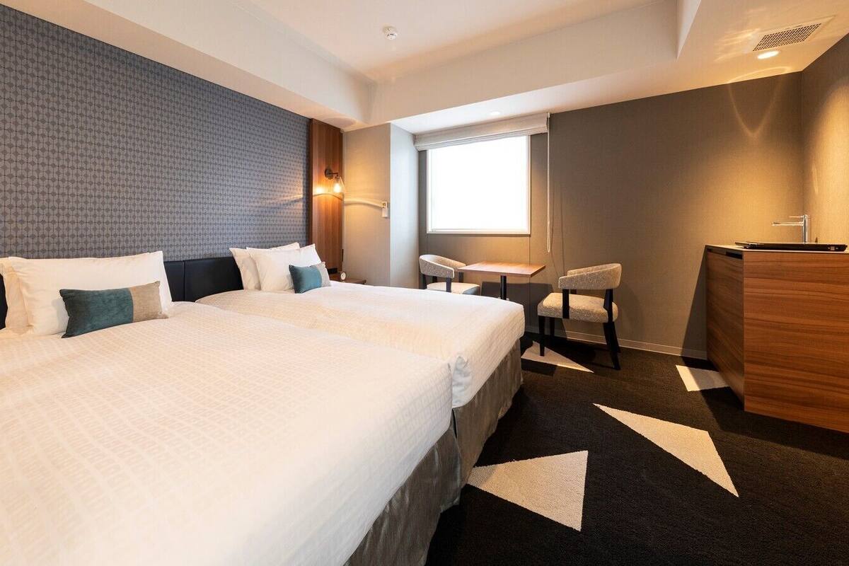 Une chambre d’hôtel avec un grand lit, un bureau, une chaise et une commode.