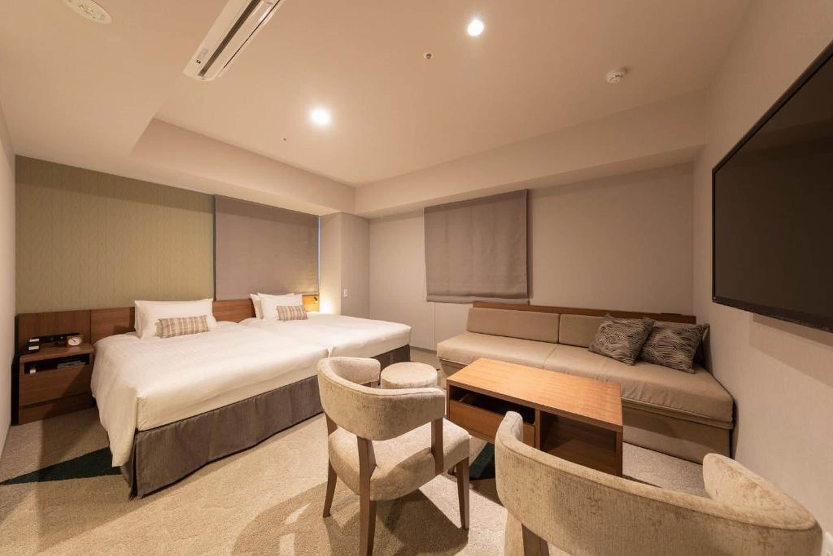 Una habitación de hotel moderna con una cama grande, un sofá, un escritorio y una silla.