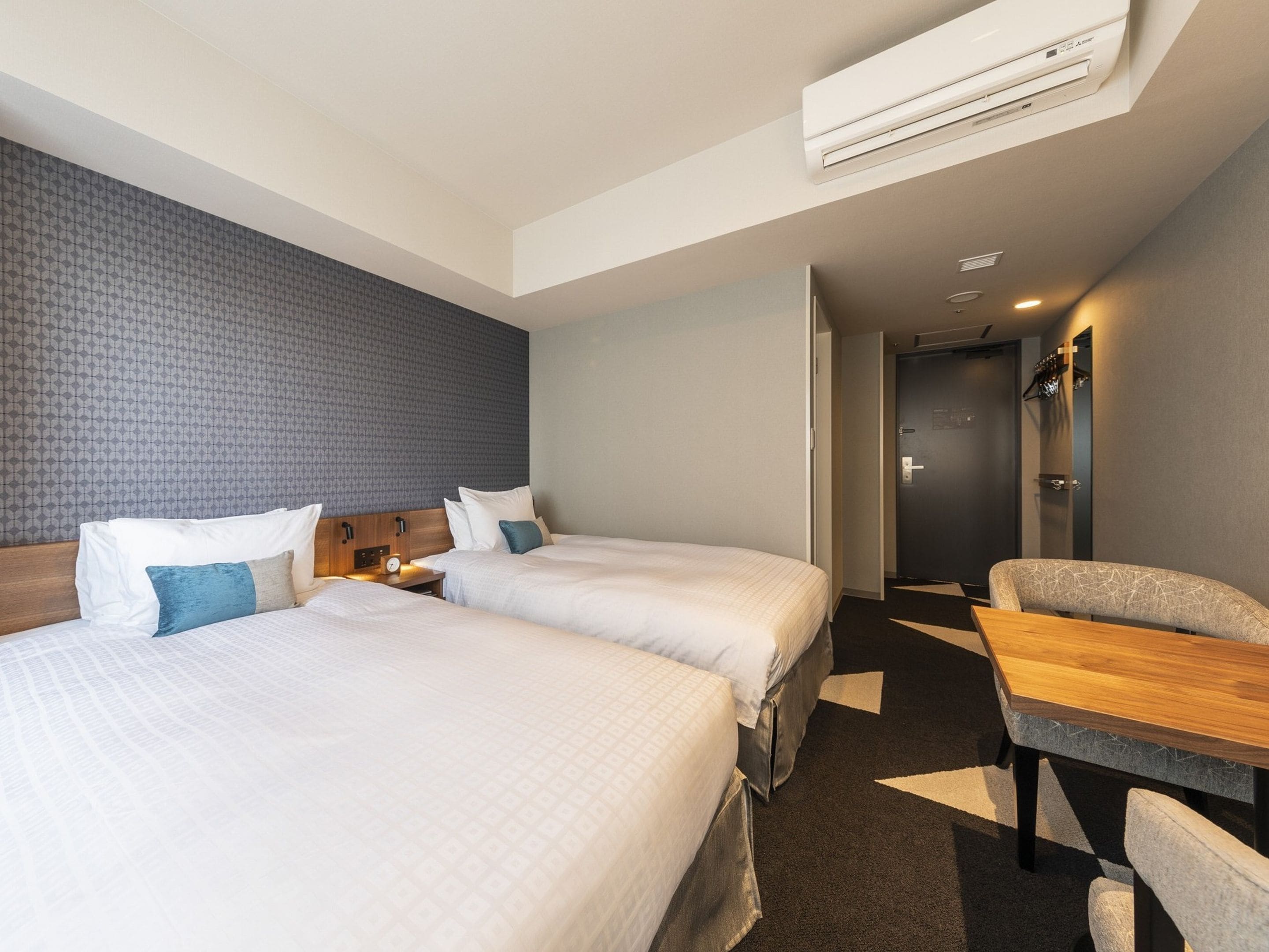 Una habitación de hotel con dos camas, un escritorio y una silla.