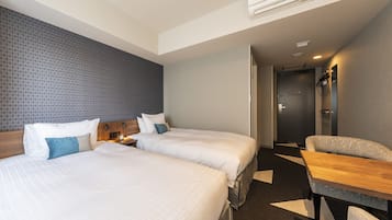 A hotel room with two beds, a desk, and a chair.