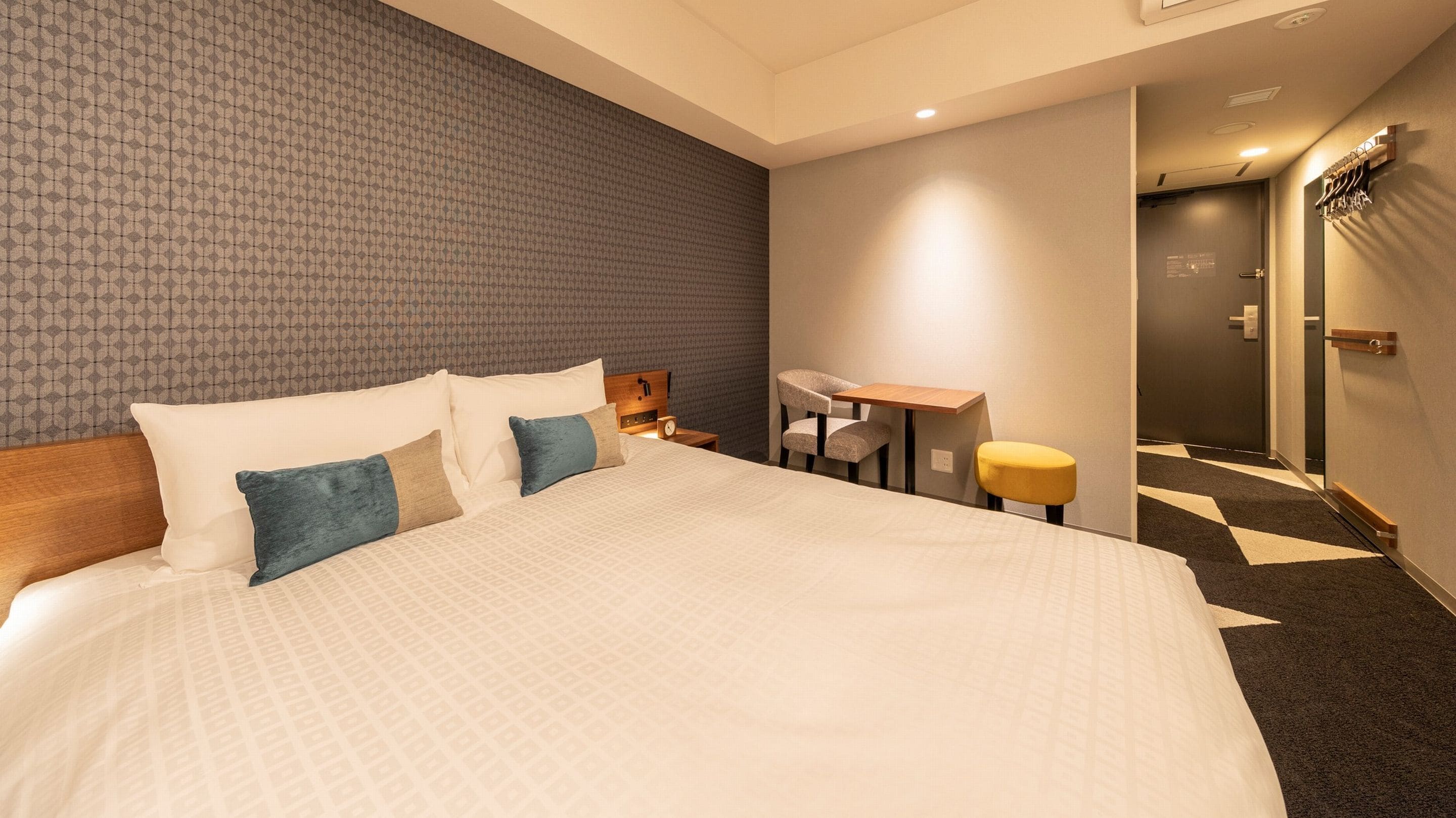 A hotel room with a large bed, a desk, and a chair.