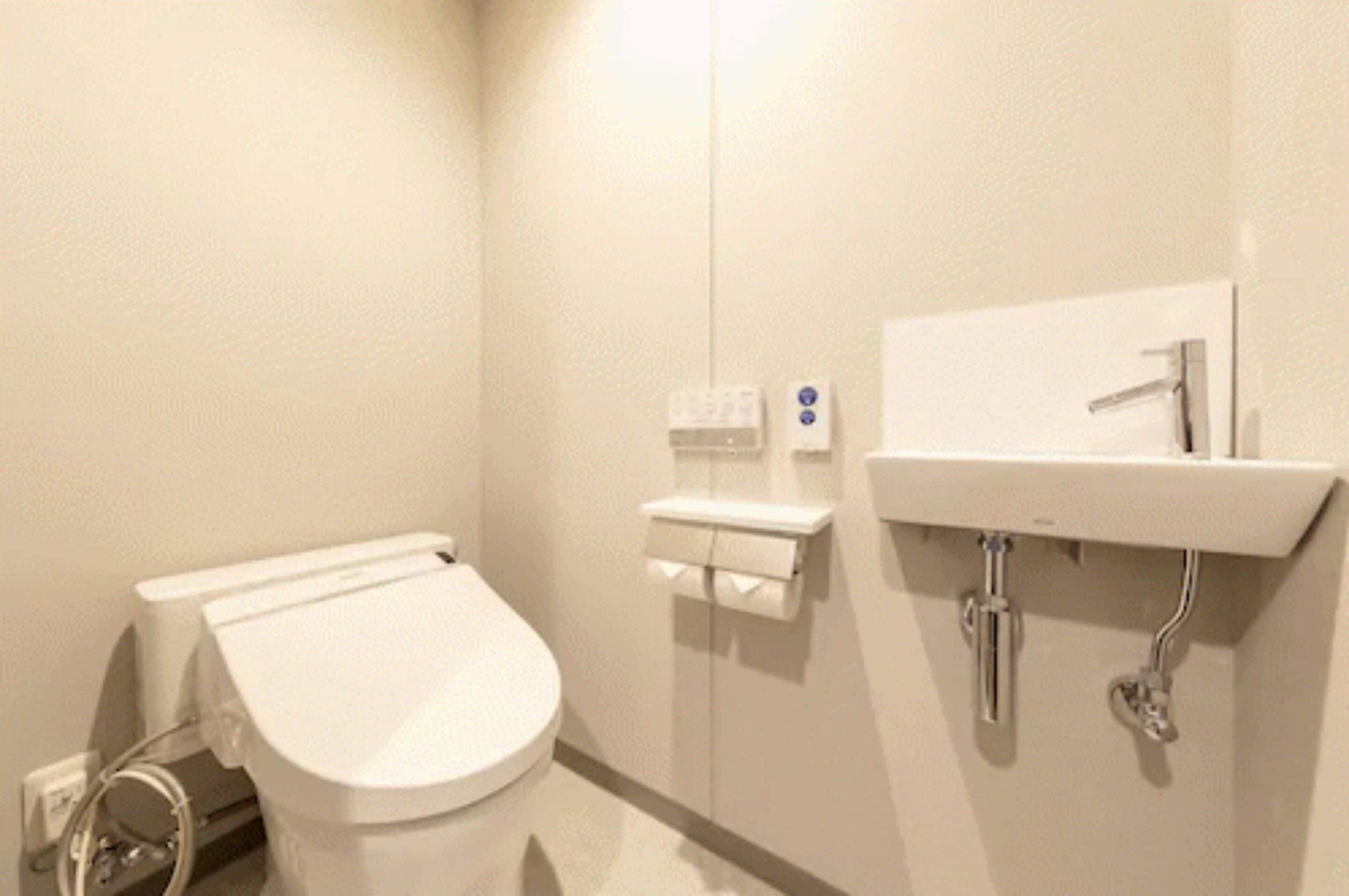 A small, clean bathroom with a toilet, a sink, and a hand dryer.