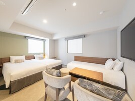 Una habitación de hotel con dos camas, una mesita, una silla y un ventanal grande.