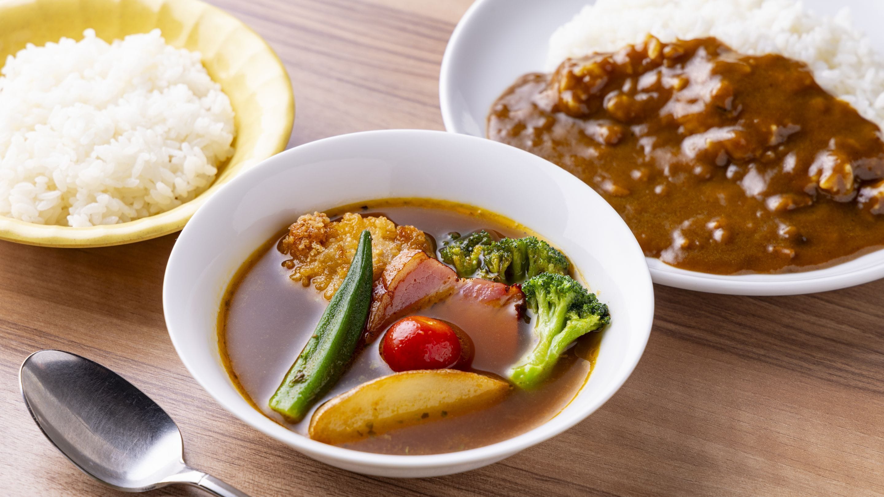 Een maaltijd met rijst, een currygerecht en een schaal met vlees, groenten en een gekookt ei.