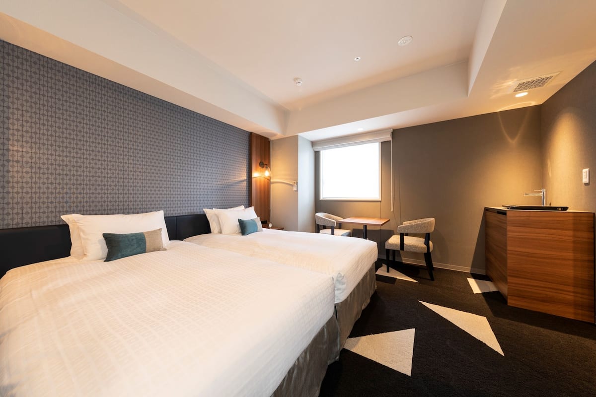 Une chambre d’hôtel avec un grand lit, un bureau, une chaise et une armoire.