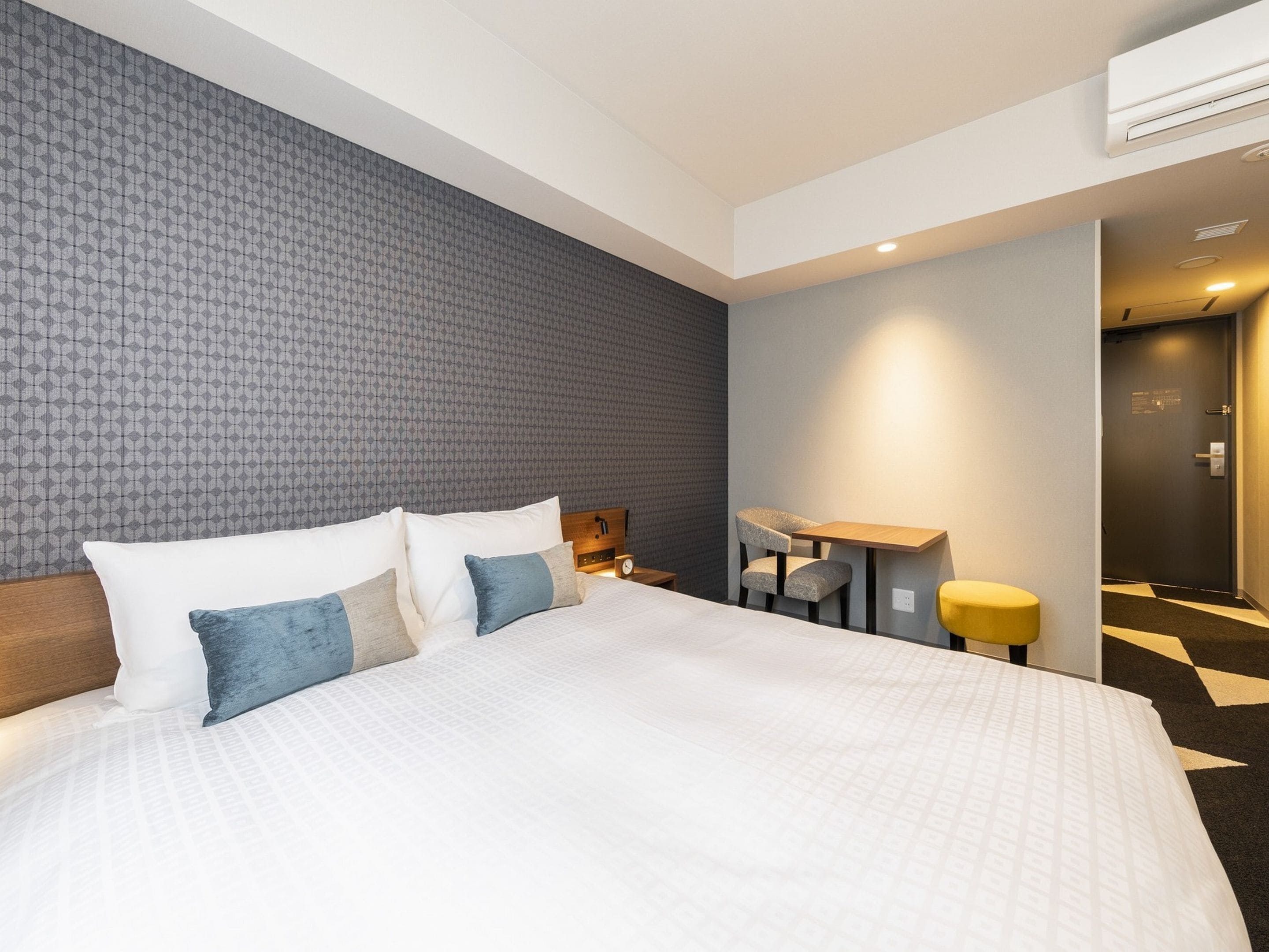 Una camera d'albergo moderna con un letto grande, una scrivania e una sedia.