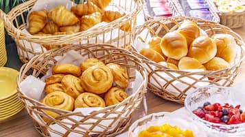 A table with baskets of pastries and bowls of fruit.