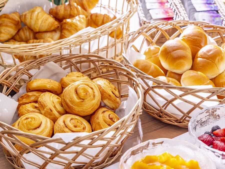 A table with baskets of pastries and bowls of fruit.