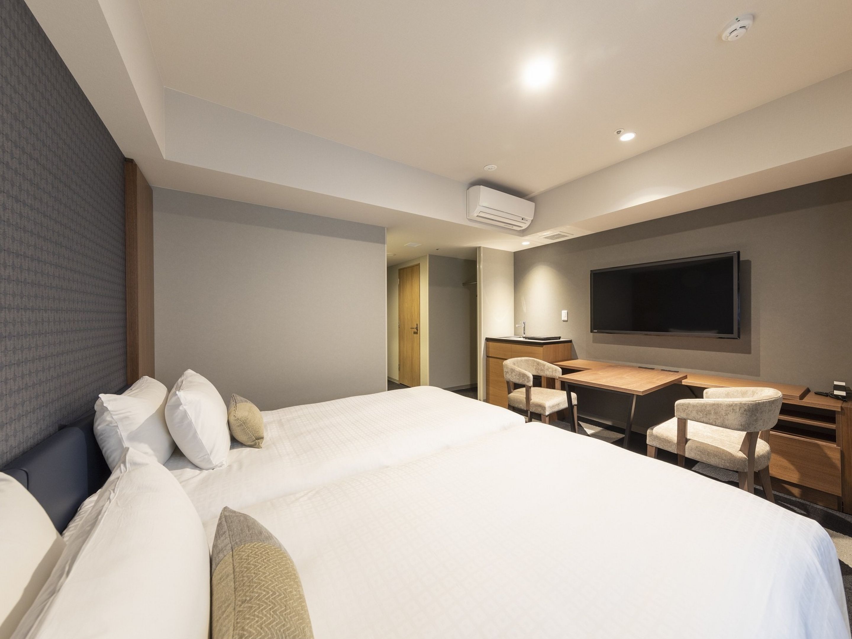 Ein modernes Hotelzimmer mit einem großen Bett, einem Schreibtisch und einem Flachbildfernseher.