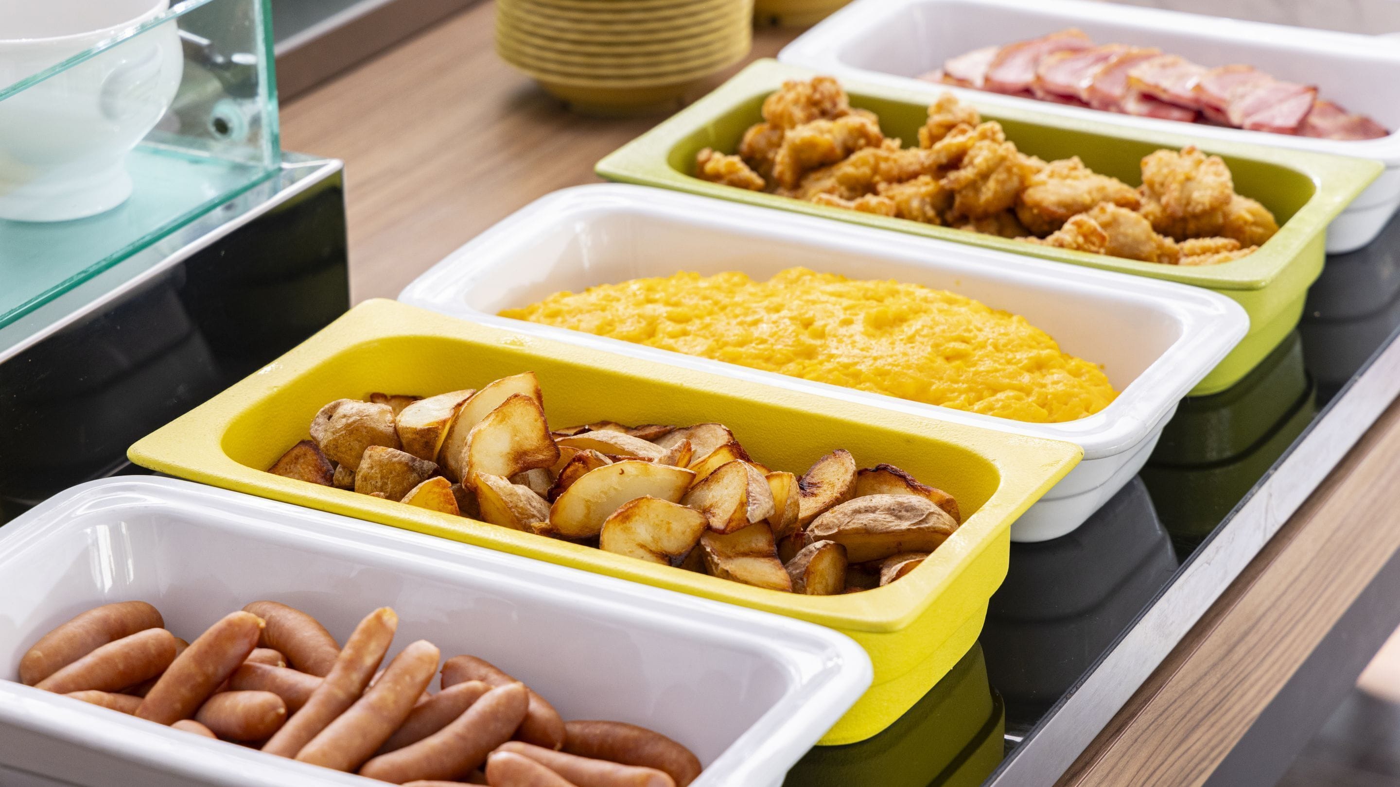 Ein reichhaltiges Buffet mit verschiedenen Speisen, darunter Kartoffeln, Würstchen und weitere Gerichte.