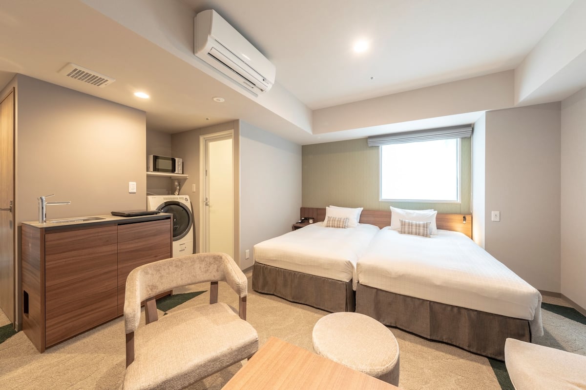Une chambre d’hôtel avec un lit double, un bureau avec une chaise, un lave-linge et un four à micro-ondes.