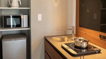 Una cocina compacta equipada con microondas, hervidor y cocina de inducción.
