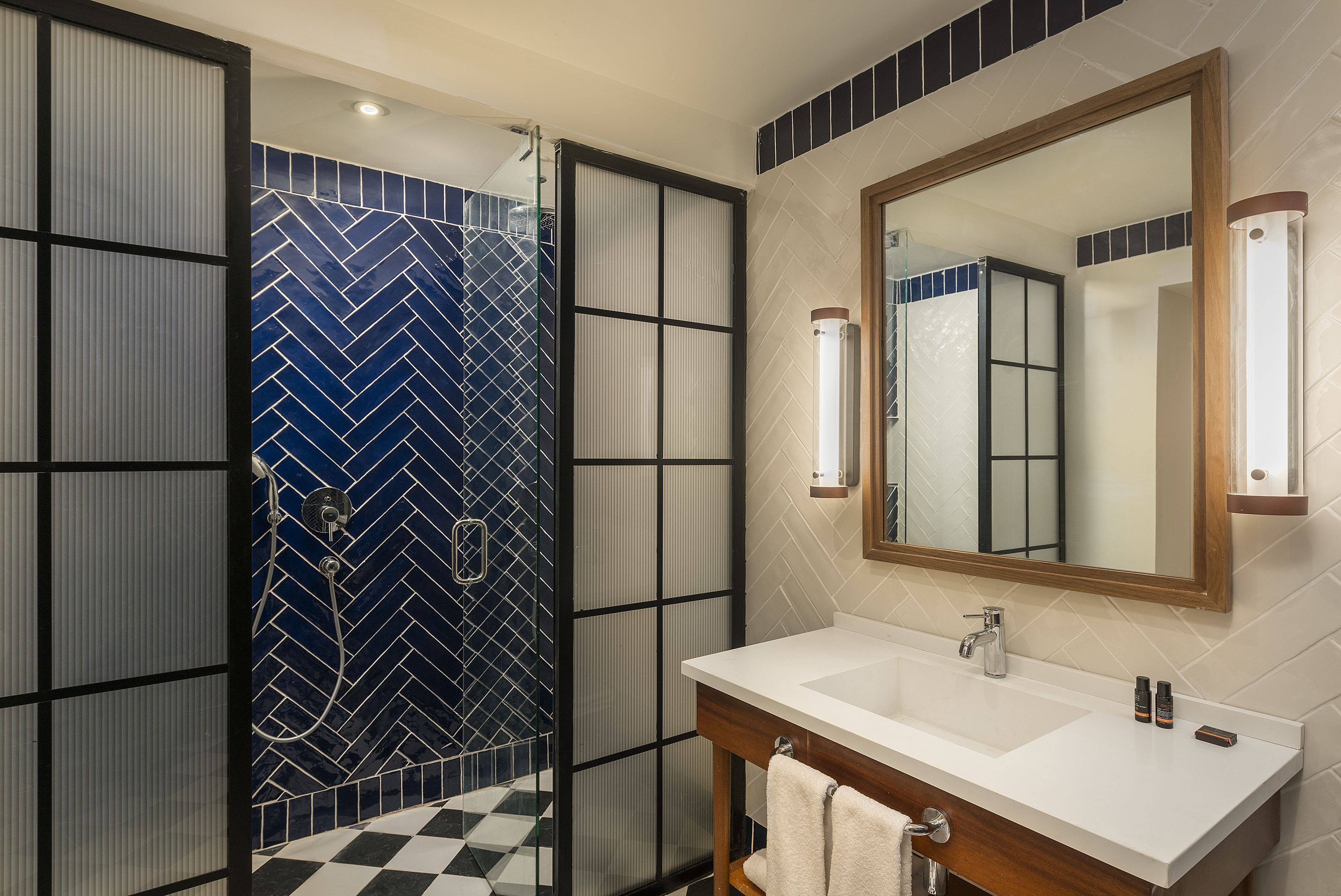 A bathroom with a white sink, a mirror, and a shower with a blue and white tile pattern.
