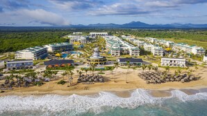 Een resort met meerdere gebouwen, een strand en uitzicht op bergen.