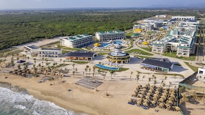 Vista aérea de um resort com vários edifícios, uma praia e área de piscina.